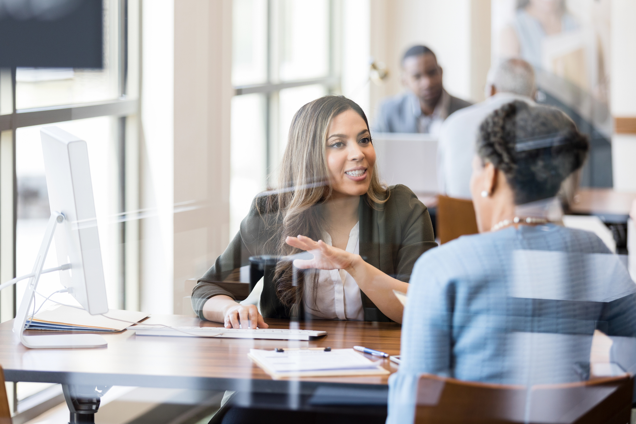 http://A%20mid%20adult%20female%20bank%20employee%20gestures%20as%20she%20explains%20banking%20services%20to%20a%20female%20customer.